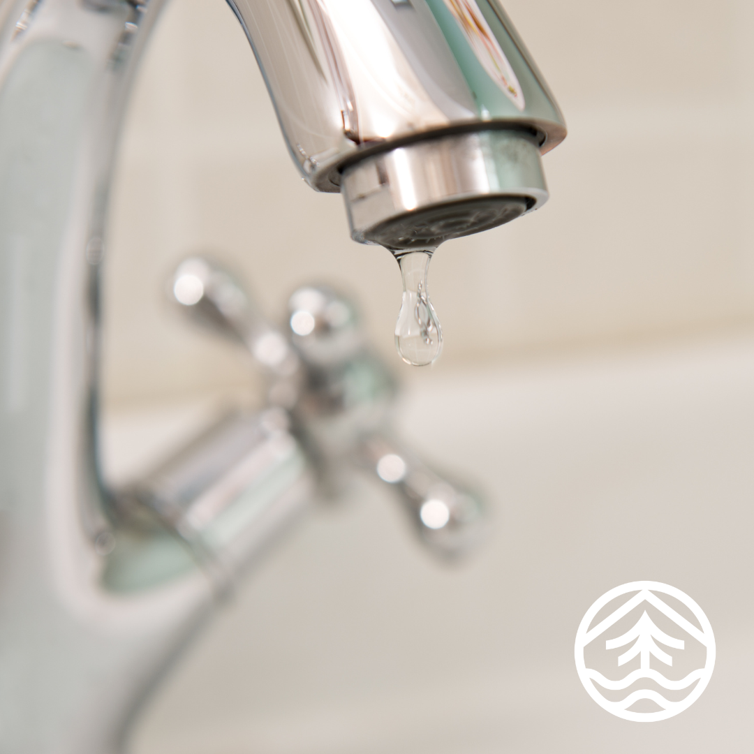 Photo of a water faucet with a drop of water coming out