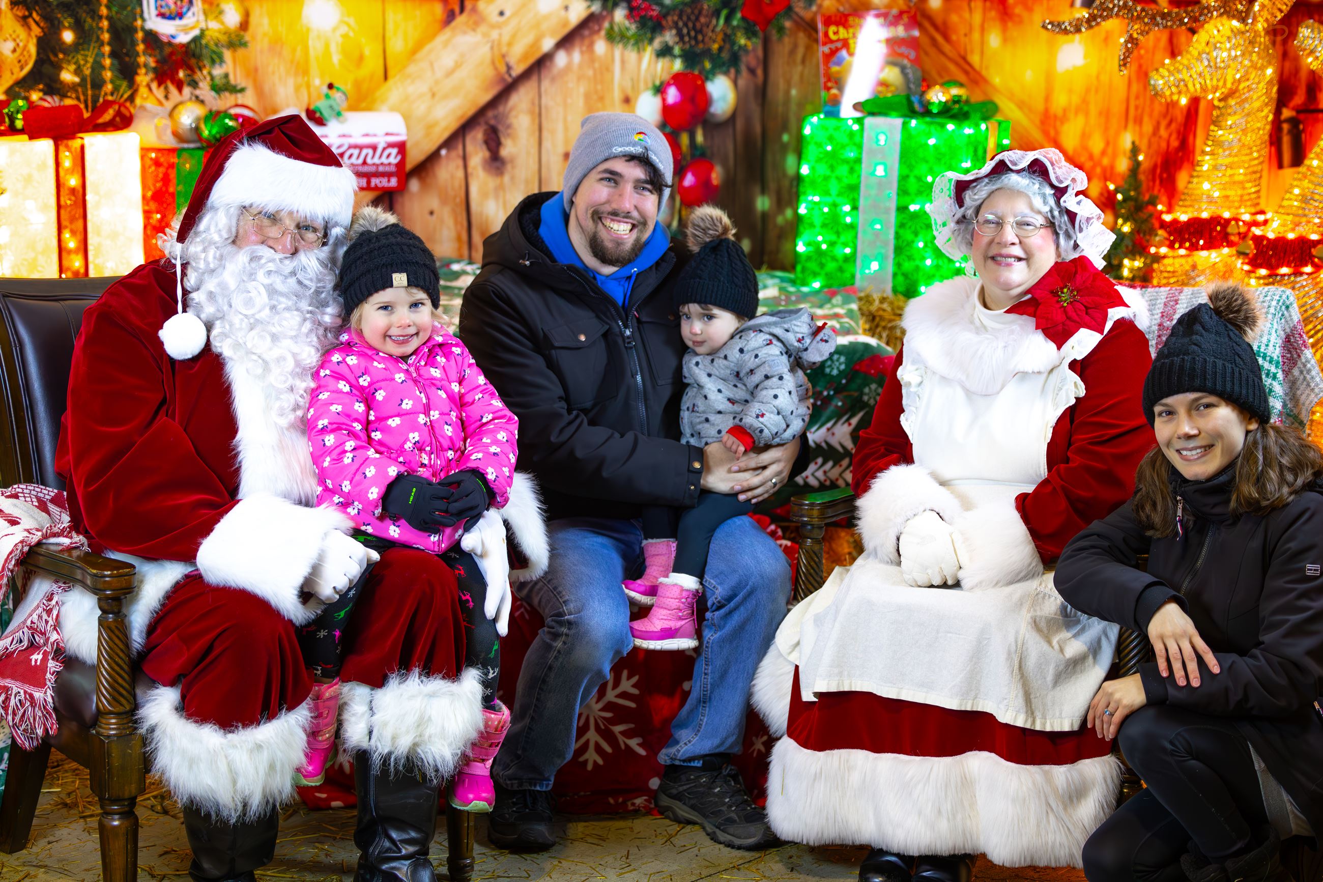 Santa and Mrs. Claus family photo with kids and parents sitting in front of holiday decorations